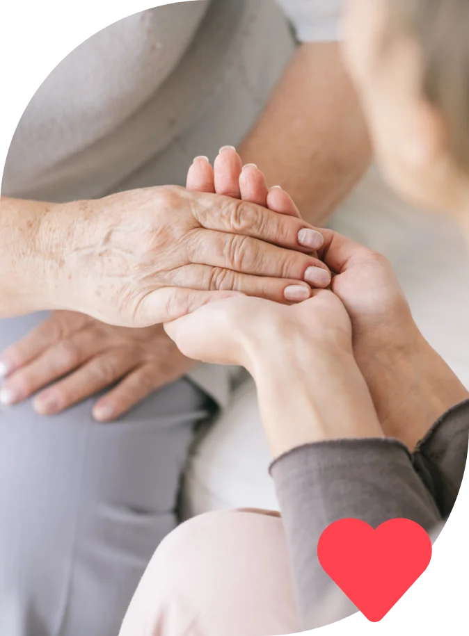 Caregiver's hands gently holding the hands of an elderly person.